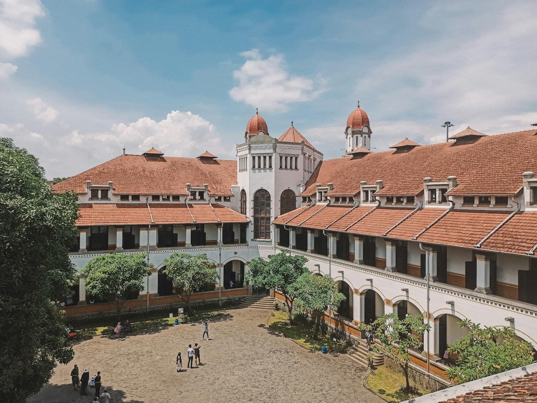Bangunan kampus bergaya lama dengan pilar tinggi dilihat dari halaman terbuka