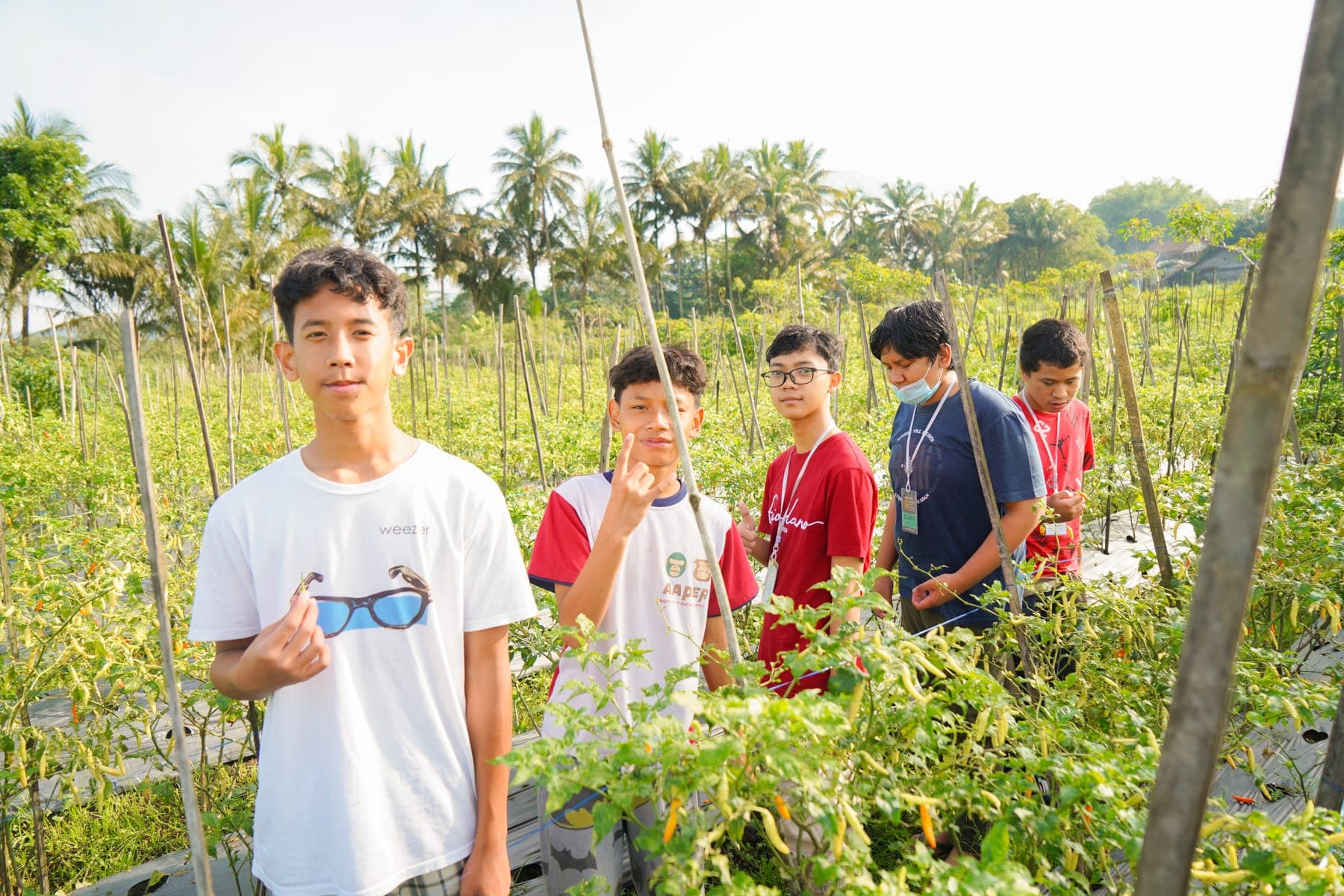 Rombongan siswa berjalan menyusuri jalur setapak di area hijau perbukitan bersama pendamping