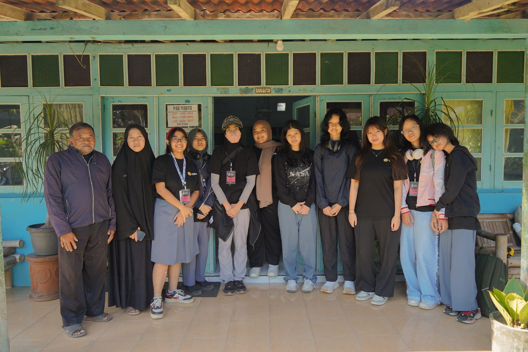 Siswa dan warga desa berfoto bersama dalam satu barisan di halaman rumah